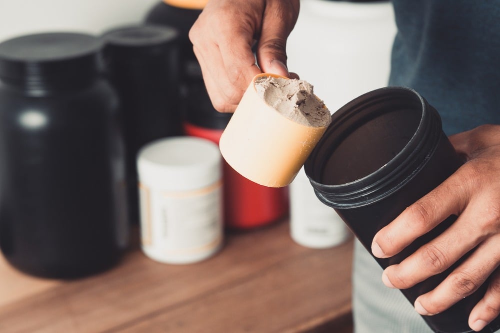 Un pratiquant de musculation en train de se préparer un shaker d'isolat de whey