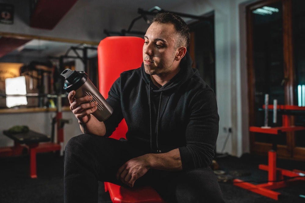 Un pratiquant de musculation prenant de la whey pendant un repos